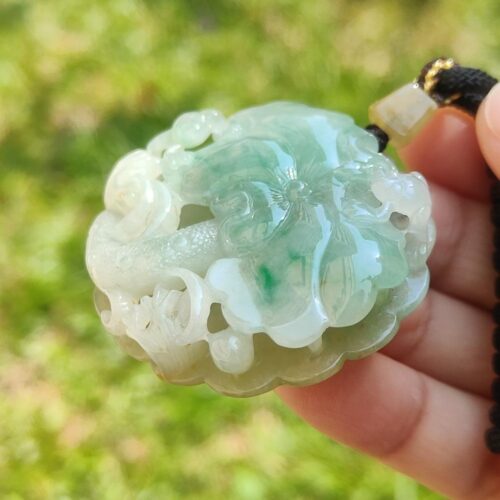 a hand holding a jade pendant
