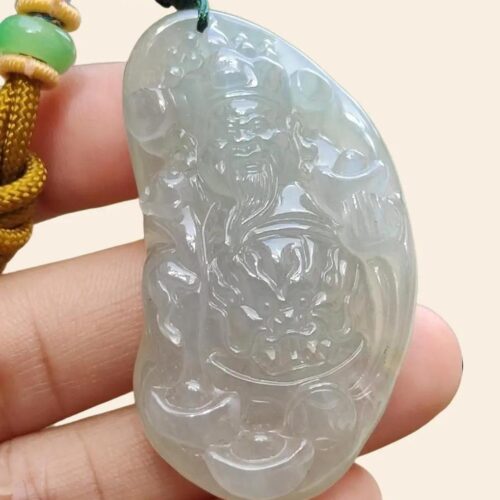 a hand holding a jade pendant
