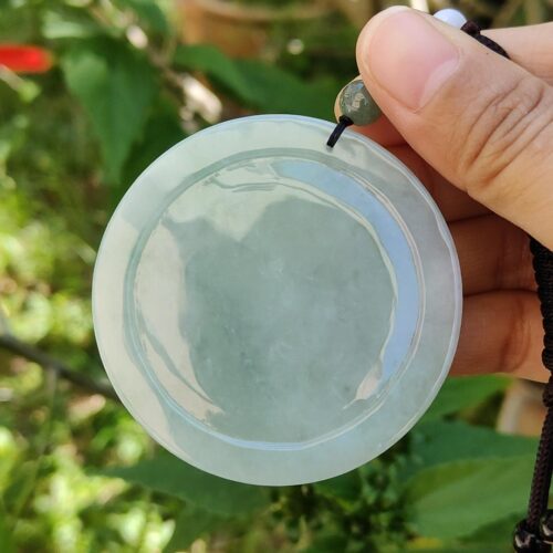 Una mano sosteniendo un colgante de jade.