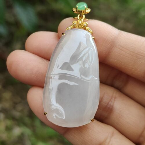 a hand holding a jade pendant