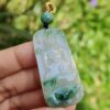 a hand holding a jade pendant
