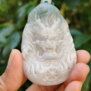 a hand holding a jade pendant