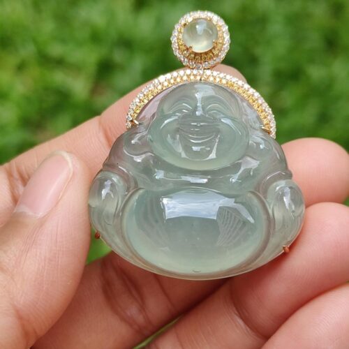 a hand holding a jade buddha pendant