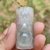 a hand holding a jade pendant