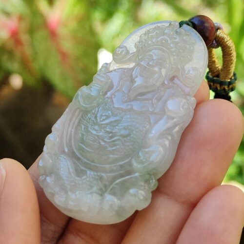 a hand holding a jade pendant