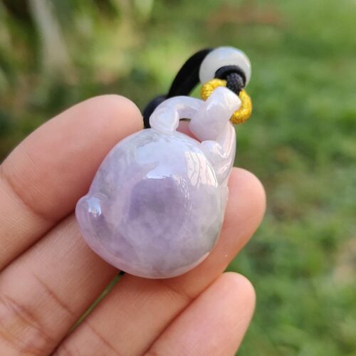 a hand holding a small purple and gold pendant
