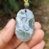 a hand holding a jade pendant