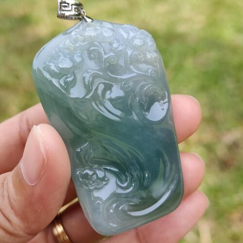 a hand holding a jade pendant