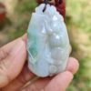 a hand holding a jade pendant