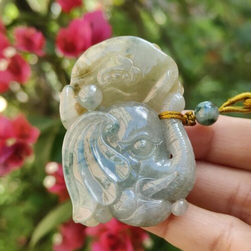 a hand holding a jade elephant pendant