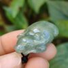 a hand holding a small green stone