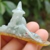 a hand holding a small jade statue
