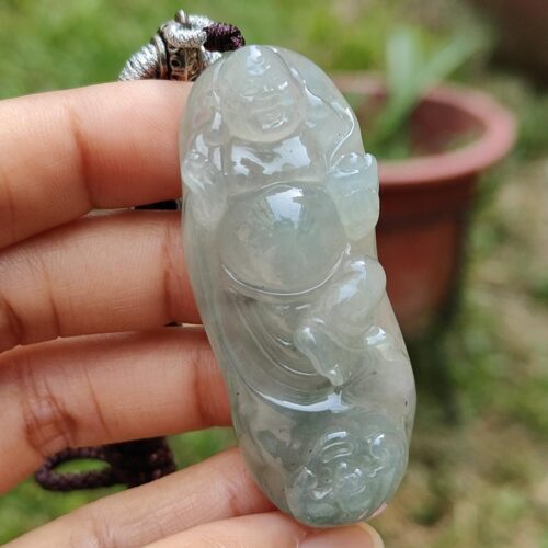 une main tenant un pendentif en jade