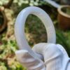 a hand in a glove holding a white ring
