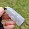 एक हाथ में जेड पेंडेंट थामे हुए