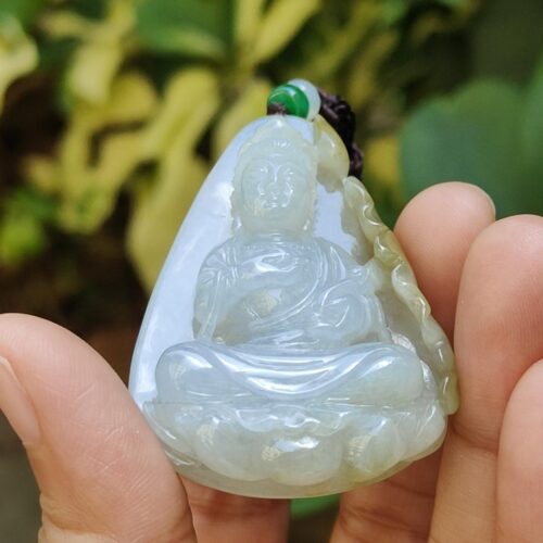 a hand holding a jade pendant
