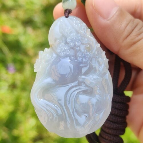 a hand holding a jade pendant