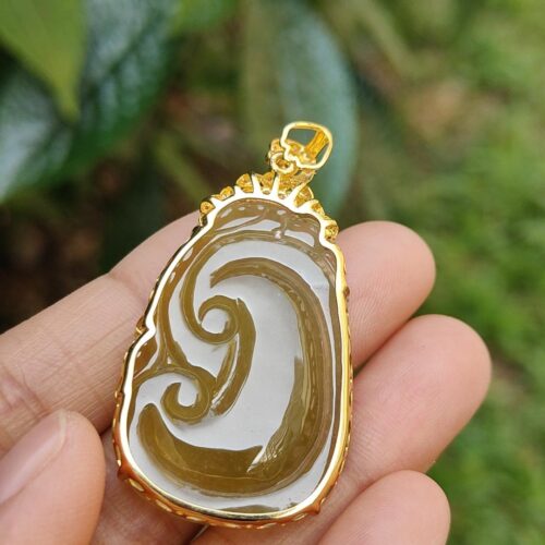 a hand holding a gold and white pendant