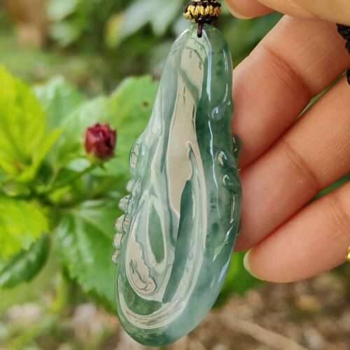 uma mão segurando um pingente de jade