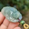 a hand holding a jade pendant
