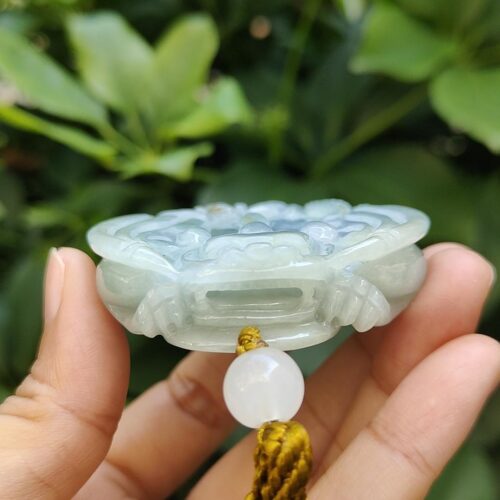 une main tenant un pendentif en jade