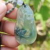 a hand holding a jade pendant