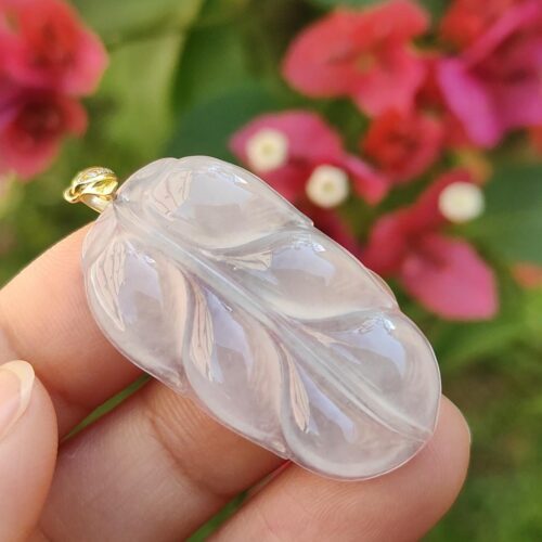 a hand holding a carved white leaf pendant
