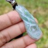 a hand holding a jade pendant