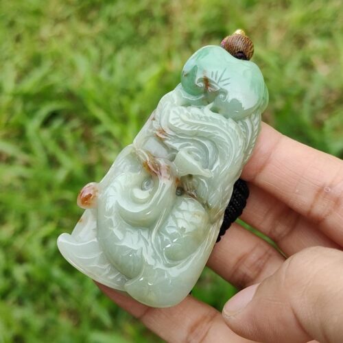 a hand holding a jade pendant