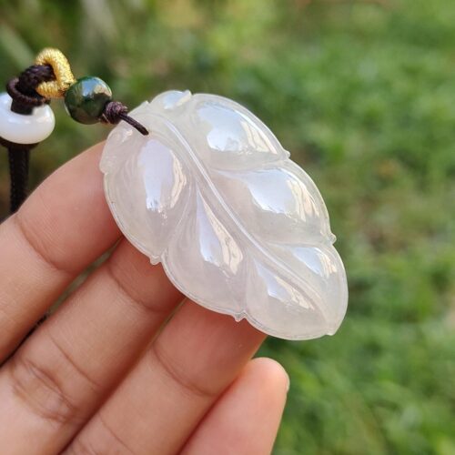 a hand holding a white carved leaf pendant