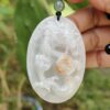 a hand holding a jade pendant