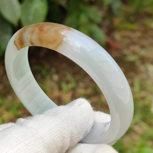 a hand wearing a glove holding a bracelet