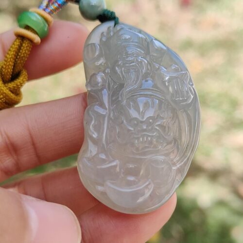 a hand holding a jade pendant
