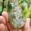 a hand holding a green and white stone