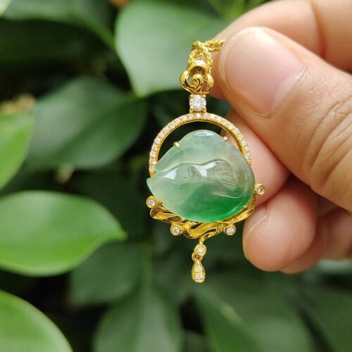 a hand holding a gold necklace with a green stone in the middle