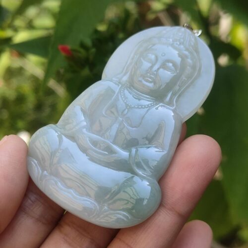 a hand holding a jade buddha pendant