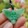 78d93976ae76b22f27ec3bcc8c1bc6b6 a hand holding a green stone pendant