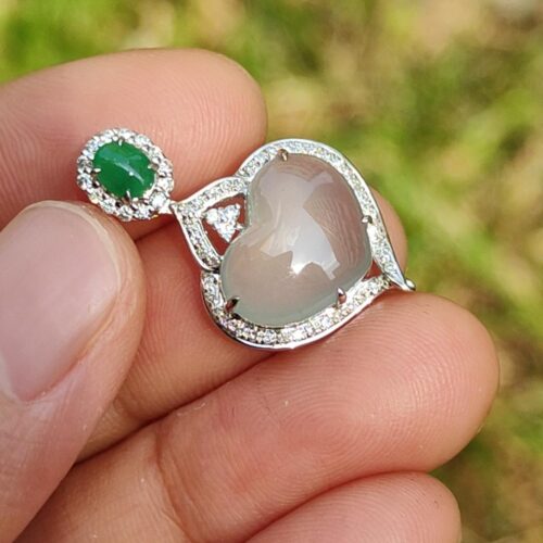 a hand holding a silver and green earring