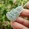 a hand holding a jade pendant