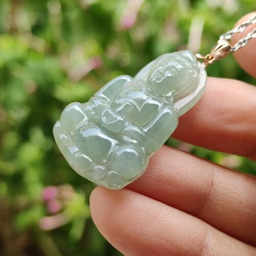 a hand holding a jade pendant