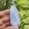 a hand holding a jade pendant