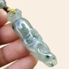 a hand holding a jade pendant