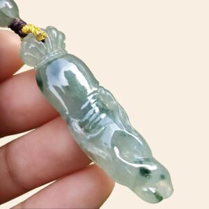 a hand holding a jade pendant