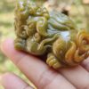 Una mano sosteniendo un pequeño animal de piedra verde.
