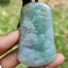 a hand holding a jade pendant