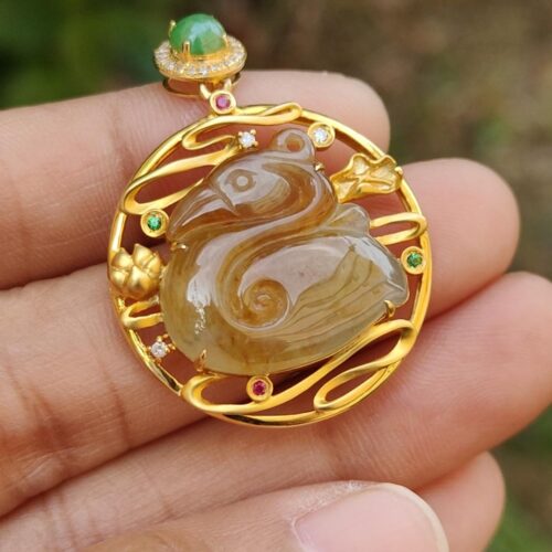 a hand holding a gold pendant with a stone in the shape of a swan