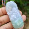 a hand holding a jade pendant
