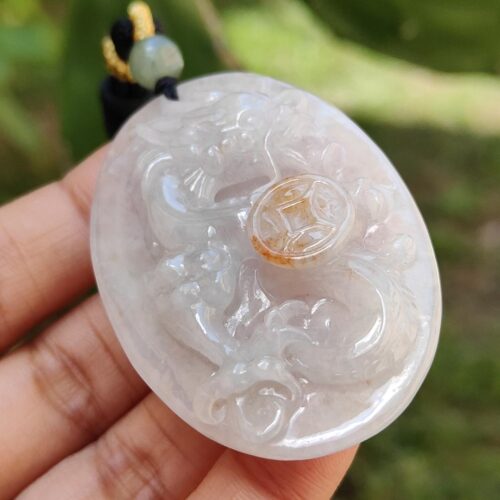 a hand holding a jade pendant
