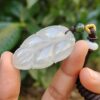 a hand holding a jade leaf pendant