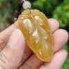 a hand holding a yellow stone pendant